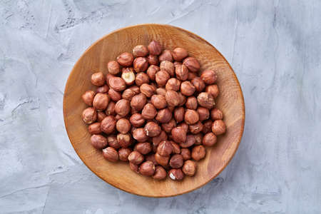 Hazelnuts in wooden bowl on white textured background with copy space, top view, close-up, selective focus, shallow depth of field. Nutritious organic snack. Vegetarian protein. Seasonal antioxidant. Healthy food concept.の写真素材