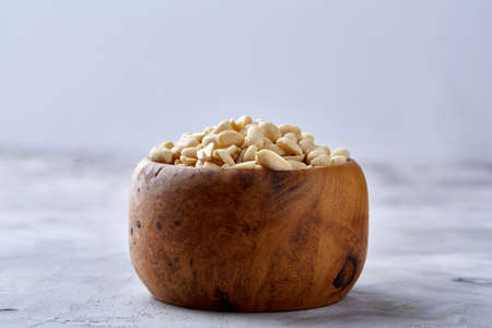Shelled peanuts in wooden plate isolated over white textured background, top view, close-up. Some copy space. Organic nutritious ingredient. Gourmet appetizer. Tasty roast snack. Healthy food conceptの写真素材