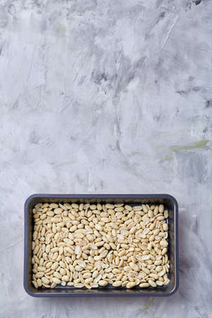 Peeled peanut on baking tray over white textured background, selective focus, shallow depth of field. Ready to bake. Healthful and nutritious snack. Delicious ready to cook nuts. Healthy lifestyle concept.の写真素材