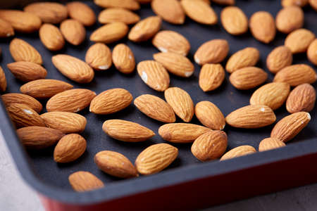 Raw almond on baking tray over white textured background, selective focus, shallow depth of field. Ready to cook. Healthful and nutritious snack. Delicious ready to cook nuts. Healthy lifestyle concept.の写真素材