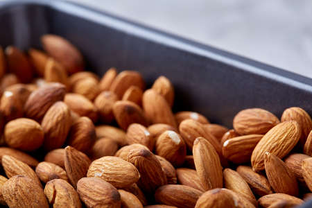 Raw almond on baking tray over white textured background, selective focus, shallow depth of field. Ready to cook. Healthful and nutritious snack. Delicious ready to cook nuts. Healthy lifestyle concept.の写真素材