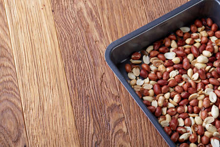 Mix of peeled raw peanut on baking tray over wooden background, selective focus, shallow depth of field. Ready to bake. Healthful and nutritious snack. Delicious ready to cook nuts. Healthy lifestyle concept.の写真素材