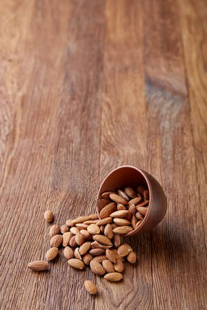 Ceramic bowl of almonds on rustic wooden background, top view, close-up, selective focus. Raw natural organic almond nuts. Healthy food for life. Some copy space. Uncooked protein. Natural oil source. Diet ingredient.の写真素材