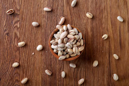 Almonds in brown bowl on rustic wooden background, top view, selective focus. Some copy space. Tasty organic snack. Healthy food for healthy life. Food concept. Natural nutritious nut. Delicious appetizer.の写真素材
