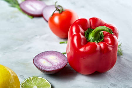 Composition of onion, pepper, tomatoes, lime, lemon isolated on white background, selective focus, flat lay, close-up. Copy space for inscription. Studio shot. Creative composition. Preparation for cooking. Healthy lifestyle concept.の写真素材