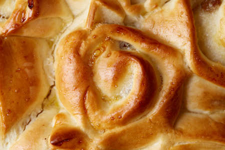 Homemade rose bread with raisins over white textured background, close-up, top view, shallow depth of field. Aromatic delicious pastry. Traditional sweet dessert. Festive background. Food concept.の写真素材