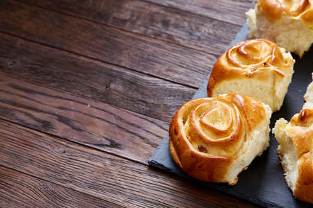 Homemade rose buns with raisins on wooden cutting board over rustic vintage background, close-up, shallow depth of field. Aromatic delicious pastry. Traditional sweet dessert. Food concept.の写真素材