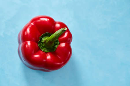Fresh red bell ped paprika on blue background, top view, close-up, selective focus. Copy space for your text. Delicious healthy appetizer. Fresh gourmet ingredient. Spring food background. Dietary product. Healthy food concept.の写真素材
