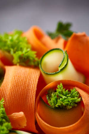 Artistically served vegetable salad with carrot, cucumber, letucce over white textured background, shallow depth of field. Some copy space. Culinary masterpiece. Restaurant serving. Gourmet low fat dish. Healthy eating dieting.の写真素材