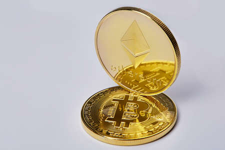 Bitcoin and Ethereum golden coins on a chart isolated on white background, selective focus,...