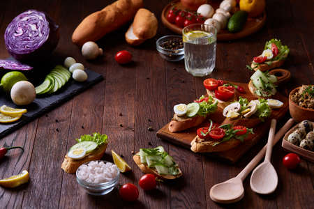 Breakfast still life with sandwiches on cutting board, quail eggs, spicies, vegetables and bowl of...