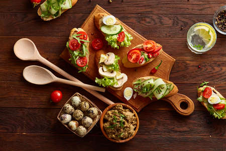 Breakfast still life with sandwiches on cutting board, quail eggs, spicies, vegetables and bowl of...