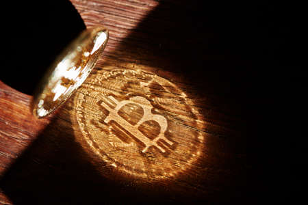 Bitcoin cryptocurrency with its shadow on wooden table, close-up, macro, selective focus, shallow depth of field. Some copy space for your inscription. Electronic commerce. Cryptocurrency concept.の写真素材