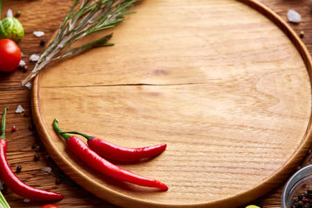 Various vegetables, seasoning cooking ingredients and salt with spicies around blank plate on light rustic wooden background, top view, selective focus, shallow depth of field. Healthy eating and diet food concept.の写真素材