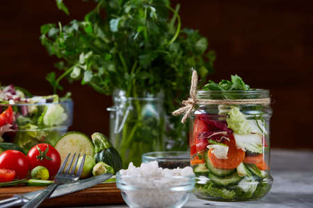 Perfect still life with fresh vegetable salad and ripe veggies on cutting board over white textured background, close up, selective focus, top view. Seasoning harvest. Preparation for cooking. Healthy dieting. Food concept.の写真素材