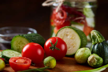 Delicious vegetable salad in jar, fresh veggies on cutting board, small sultanas with salt and...