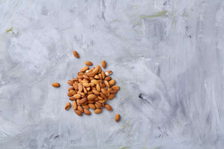 A pile of shelled almond nuts isolated against white textured background, close-up, top view,...
