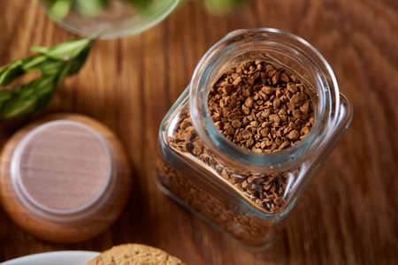 Open jar of instant coffee arranged on woden table, top view, close-up, selective focus, shallow...