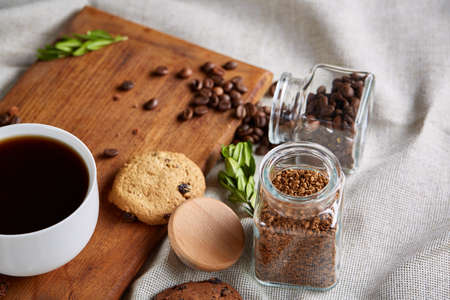 Breakfast background with porcelain mug of fresh black coffee, homemade oatmeal cookies on cutting...