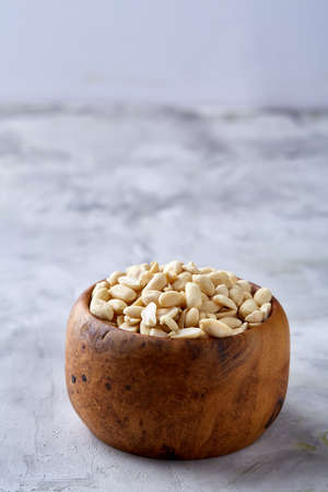 Shelled peanuts in wooden plate isolated over white textured background, top view, close-up. Some copy space. Organic nutritious ingredient. Gourmet appetizer. Tasty roast snack. Healthy food conceptの写真素材