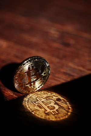 Bitcoin cryptocurrency with its shadow on wooden table, close-up, macro, selective focus, shallow depth of field. Some copy space for your inscription. Electronic commerce. Cryptocurrency concept.の写真素材