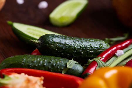 Creative fresh vegetable salad with ruccola, cucumber, tomatoes and raddish on white plate over wooden background, close-up, selective focus. Morning atmospheric lighting, fashionable trendy spot. Preparation for design creative menu. Food conceptの写真素材