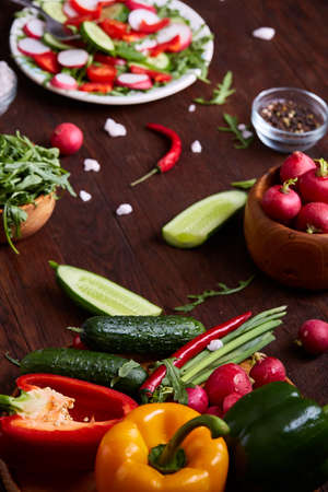 Creative fresh vegetable salad with ruccola, cucumber, tomatoes and raddish on white plate over...