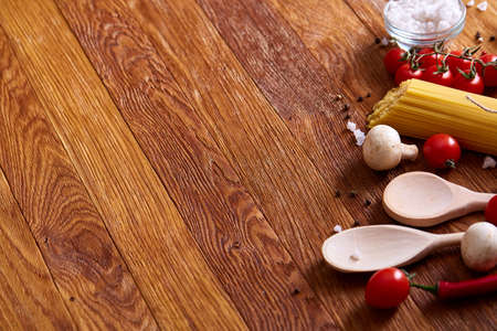 Uncooked pasta, tomatoes and spice on wooden background, top view, close-up, selective focusの写真素材