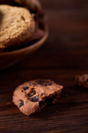 Side view of chocolate chip cookies on a wooden plate over rustic background illuminated with...