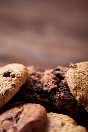 Side view of chocolate chip cookies on a wooden plate over rustic background illuminated with...