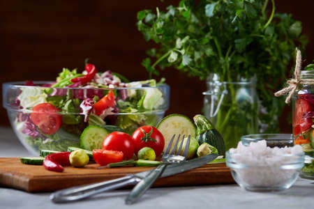 Fresh vegetable salad and ripe veggies on cutting board over white background, close up, selective focusの写真素材