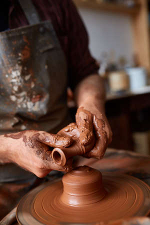 Portrait of a male potter in apron molds bowl from clay, selective focus, close-upの写真素材