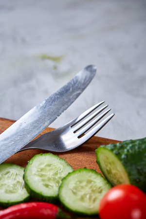 Fresh vegetable salad and ripe veggies on cutting board over white background, close up, selective focusの写真素材