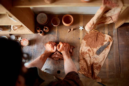 Portrait of a male potter in apron molds bowl from clay, selective focus, close-upの写真素材