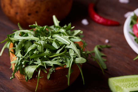 Fresh red radish in wooden bowl among plates with vegetables, herbs and spicies, top view, selective focus.の写真素材