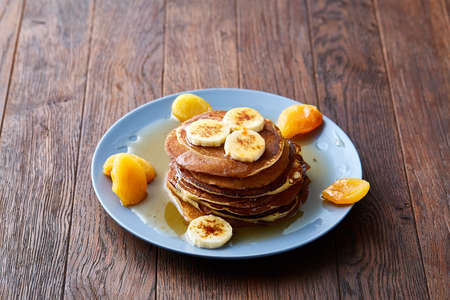 Pile of homemade pancakes with banana and walnuts on blue background, selective focusの写真素材
