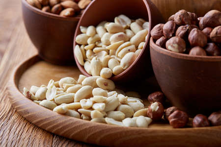 A composition from different varieties of nuts in a wooden bowls on rustic background, close-up,...