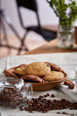 Roasted coffee beans get out of overturned glass jar on homespun tablecloth, selective focus, side...