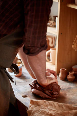 Hands of male potter molding a clay in pottery workshop, close-up, selective focus