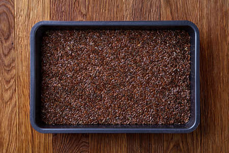 Nutritious flaxseed on baking tray over wooden background, selective focus, shallow depth of field. Nutritious and deitary ingredient. Natural organic condiment. Healing oilseed. Healthy lifestyle concept.の写真素材
