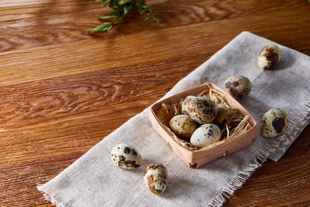 Quail eggs in the container over rustic wooden table, close-up, high angle view, selective focus.