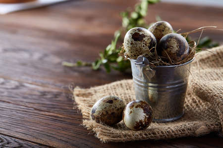 Spring composition of quail eggs in bucket on a linen napkin and boxwood branch, selective focusの写真素材