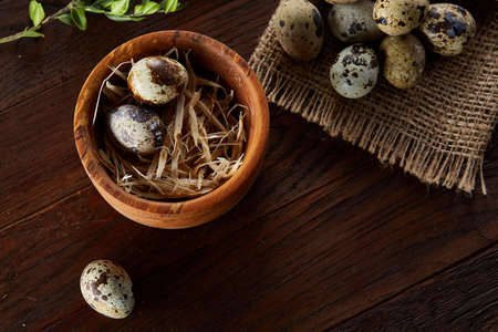 Rural still life with bowl full of eggs quail, eggs on a homespun napkin, boxwood on wooden background, top viewの写真素材