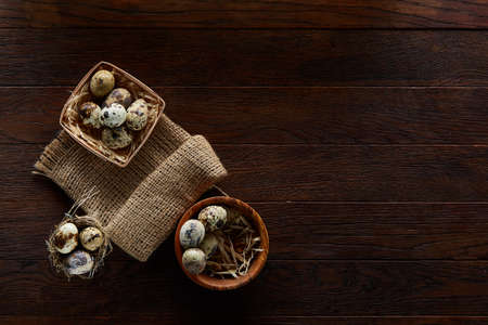 Rustic still life with quail eggs in bucket, box and bowl on a linen napkin over wooden background, selective focusの写真素材