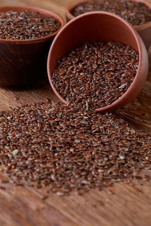 An overturned ceramic bowl with linseeds on a rustic background, close-up, shallow depth of field, selective focusの写真素材