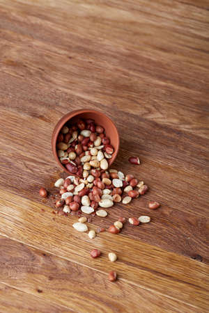 Two ceramic bowls with raw peanuts mix isolated over rustic wooden backround, top view, close-up.の写真素材