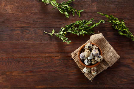 Bowl with eggs quail, eggs on a homespun napkin, boxwood on wooden background, close-up, selective focus, top viewの写真素材