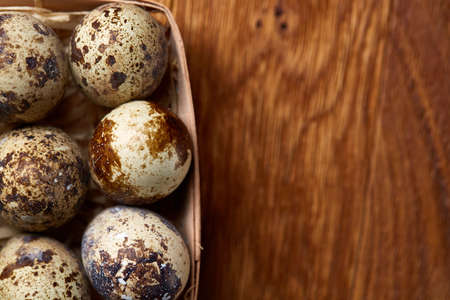 Spotted quail eggs arranged in rows in a box on a rustic wooden background, top view, selective focus, shallow depth of field. Some copy space tor your inscription. Textured background emphesize the still life. Healthy lifestyle concept.の写真素材