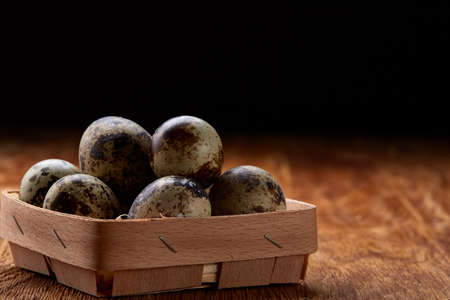 Spotted quail eggs arranged in rows in a box on a rustic wooden background, top view, selective focus, shallow depth of field. Some copy space tor your inscription. Textured background emphesize the still life. Healthy lifestyle concept.の写真素材