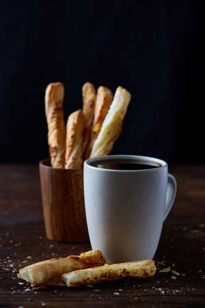Coffee cup and breadsticks on an old wooden background, close-up, selective focus.の写真素材